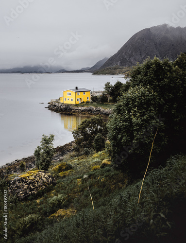 Gelbes Haus an einem Fjord in Norwegen umgeben von Wasser Bergen und mit Spiegelung photo