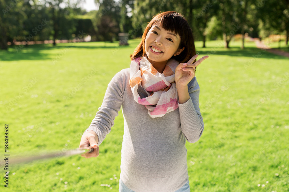 happy pregnant asian woman taking selfie at park happy pregnant asian woman taking selfie at park
