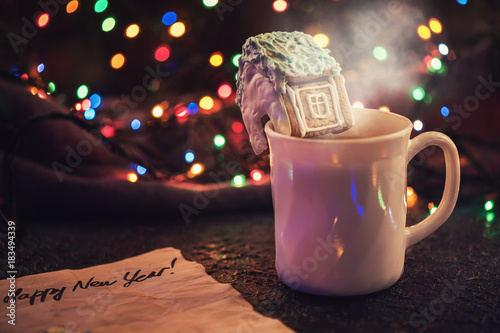 Christmas cookies and cup of tea on daark color bokeh lights background photo