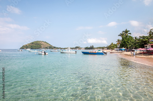 Sandstrand von der Insel Nosy Be  Madagaskar mit Booten  Urlaubern  Palmen und blaues Wasser