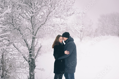 A loving couple on a winter walk. Snow love story, winter magic. Man and woman on the frosty street. The guy and the girl are resting on the snow. Christmas mood of a young family. © tatyana_k