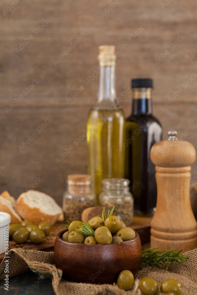 Green olives in bowl with oil bottles in background Green olives in bowl with oil bottles in background