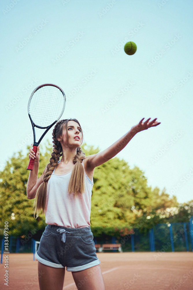 Girl in sportswear serves tennis ball