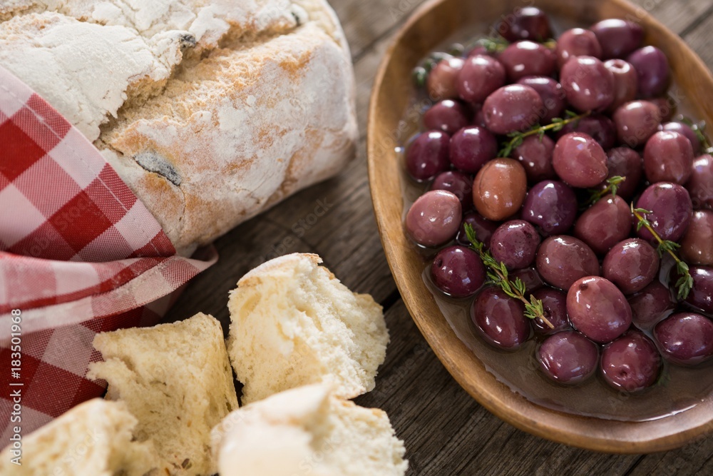 Fototapeta premium Marinated olives with bread loaf on wooden table