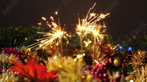 Burning bengal fire on a background of the christmas decoration with garland. The bright lights of Christmas on the black background. photo