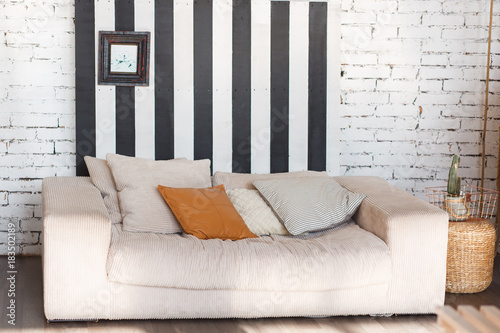 Loft modern interior with white brick wall, black stripes and sofa in front.