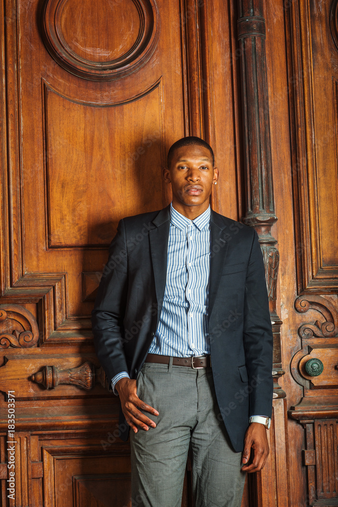 African American businessman working in New York. Wearing black blazer,  shirt, gray pants, a young school teacher standing by vintage style  classroom, looking forward. Portrait of Graduate Student. Stock Photo |  Adobe