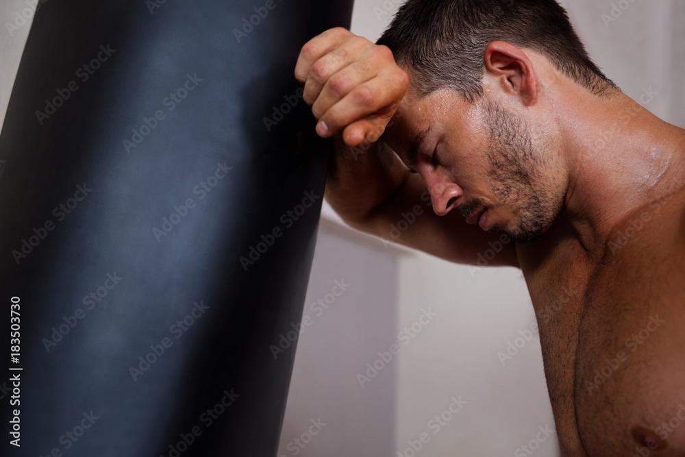 Fototapeta premium Tired man leaning on punching bag