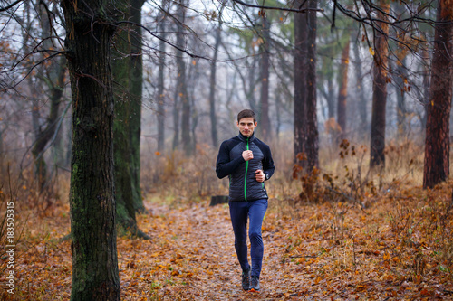 Young running man in fall park. Jogging in cold and misty weather © skumer