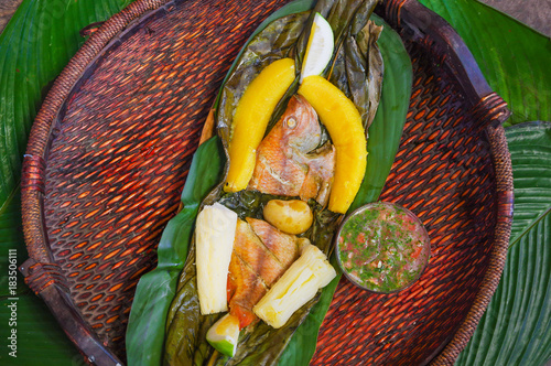 Photography Above view of delicious typical amazonian food, fish cooked in a leaf with yucca