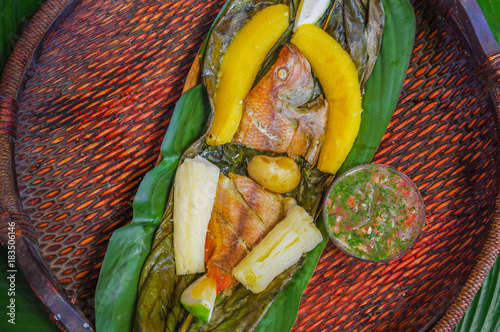 Canvas Print Above view of delicious typical amazonian food, fish cooked in a leaf with yucca