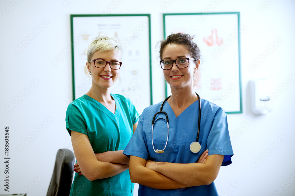 Φωτογραφία Portrait of two professional happy nurses with eyeglasses standing in the office with crossed arms an looking at the camera