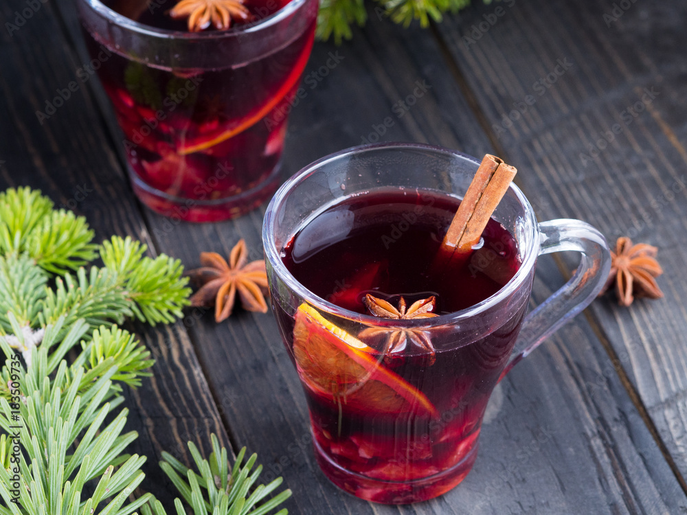 Two glasses of mulled red wine with cinnamon, orange and star anise on wooden table. Christmas and New Year drink. Two glasses of mulled red wine with cinnamon, orange and star anise on wooden table. Christmas and New Year drink.