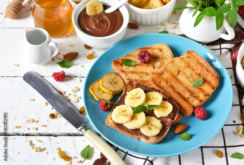 Good morning - toast with walnut, chocolate paste, banana and honey. White food background.