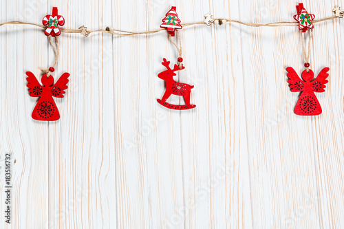Christmas wooden red toys in the shape of a deer and an angelic rope on a white wooden background. Beautiful festive greeting card with free space