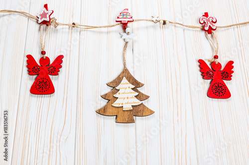 Christmas wooden toys are hung on a rope on a white wooden background. Beautiful festive greeting card with free space