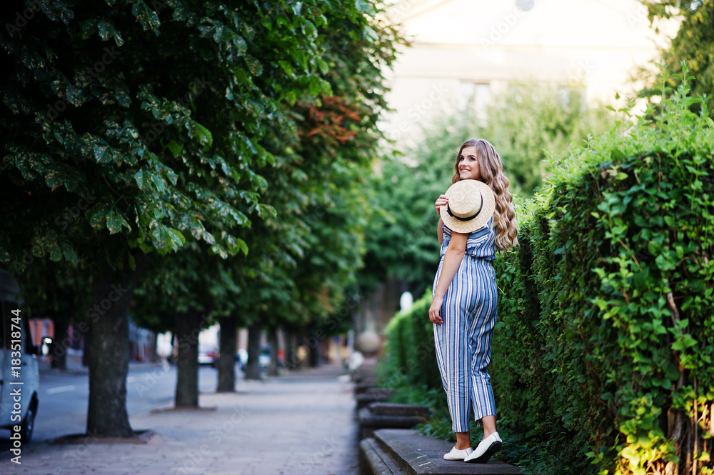Obraz premium Portrait of a fabulous young woman in striped overall walking on the barrier in the park.