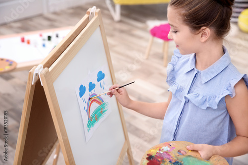 Little girl painting rainbo...