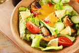 Delicious salad with honey mustard dressing in wooden bowl, closeup