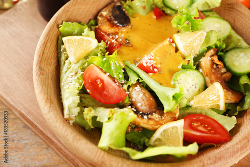 Delicious salad with honey mustard dressing in wooden bowl, closeup