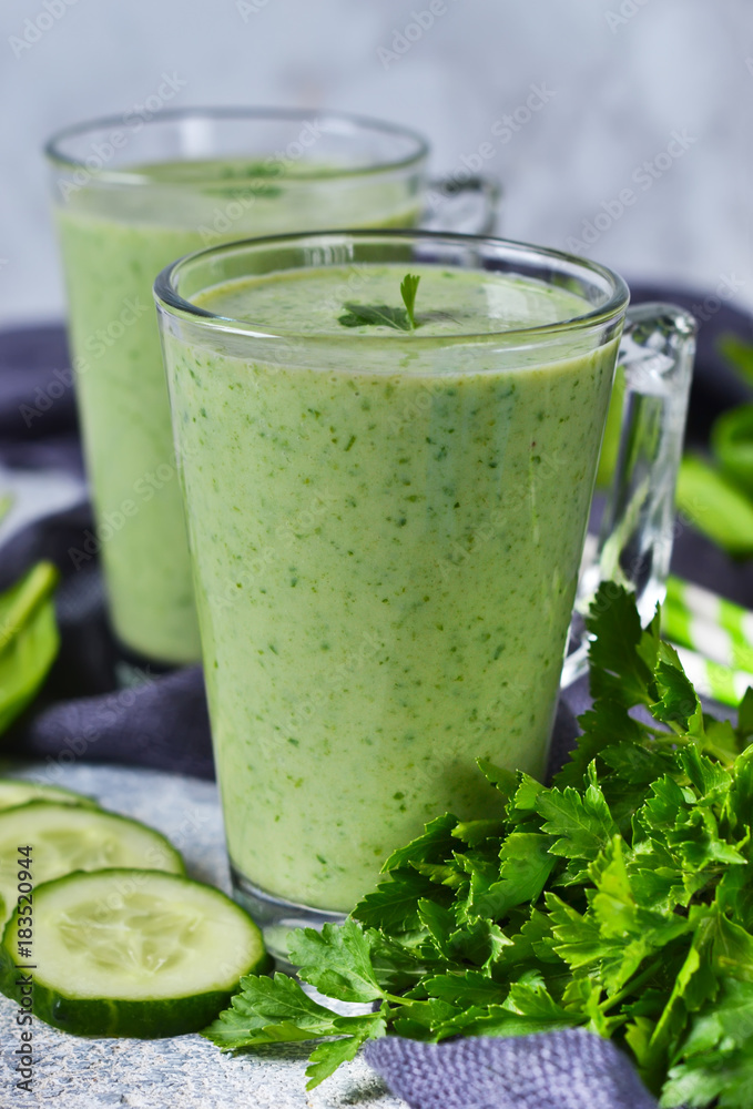 Green vegetable smoothie with avocado, cucumber and spinach on a gray background Green vegetable smoothie with avocado, cucumber and spinach on a gray background