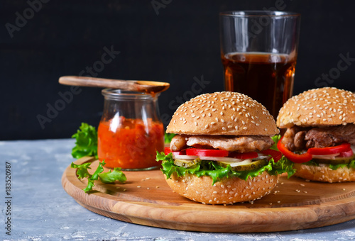 Big homemade burger with meat, tomato and sauce on a cutting board. Concrete background. Fast food.