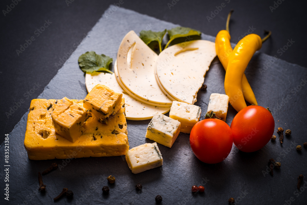 Cheese with mold, cherry tomatoes, basil and melissa greens, red hot pepper  on a stone tray on a dark gray background Stock Photo | Adobe Stock