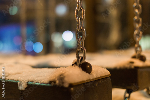 Snow-covered pendant on chains in the playground