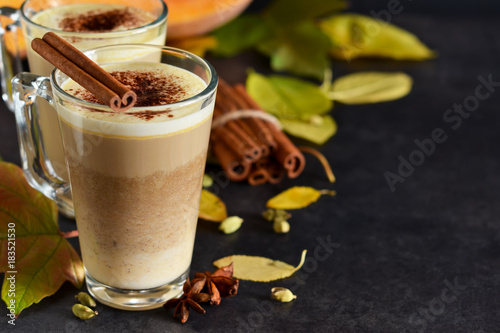 Warm, spicy drink - latte with cinnamon and pumpkin on a black background