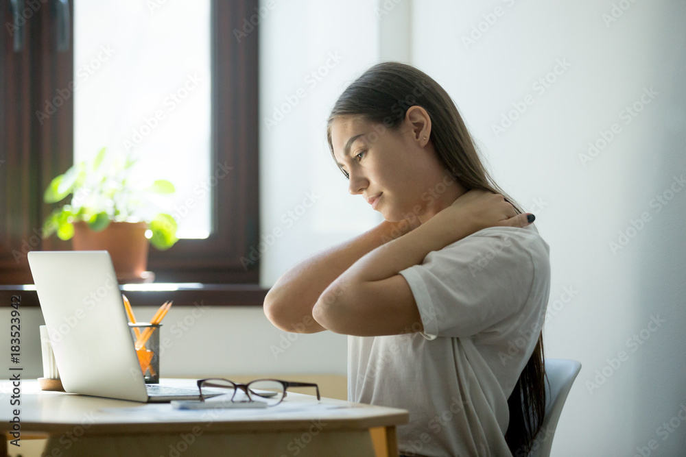 Overwork, sedentary lifestyle concept: millennial businesswoman stretching body, feeling back pain, massaging neck at workplace. Young female manager having rest in home office after finishing her job Overwork, sedentary lifestyle concept: millennial businesswoman stretching body, feeling back pain, massaging neck at workplace. Young female manager having rest in home office after finishing her job