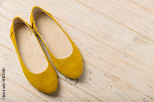 Yellow women's shoes (ballerinas) on wooden background.