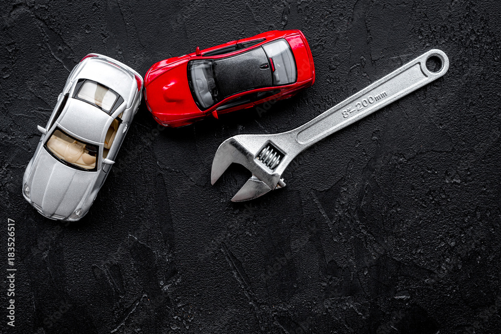 Car repair concept. Wrench near car toys on black background top view copyspace