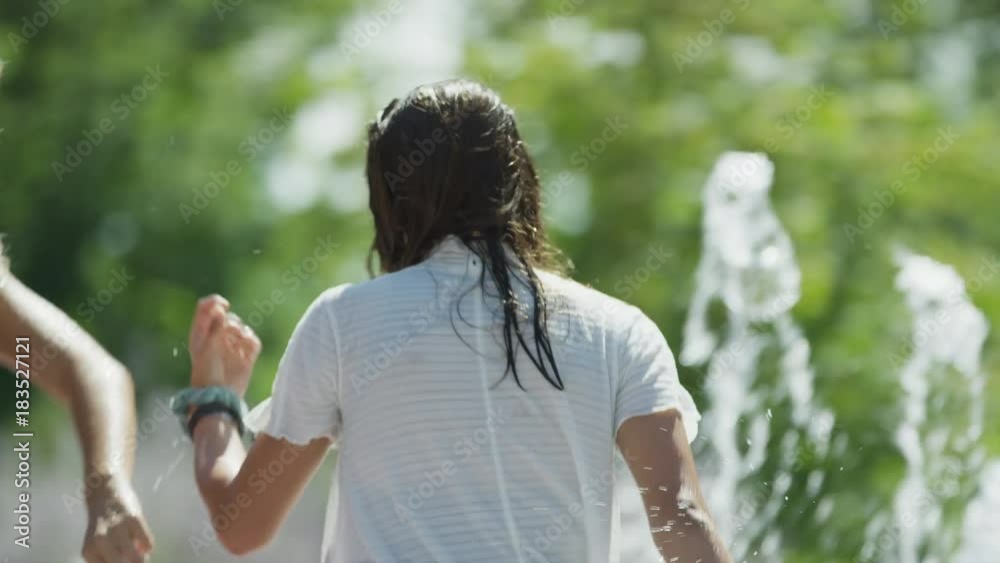 Girls walking and splashing in park fountain / Provo, Utah, United States