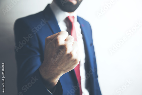Business manager with clenched fist on dark background