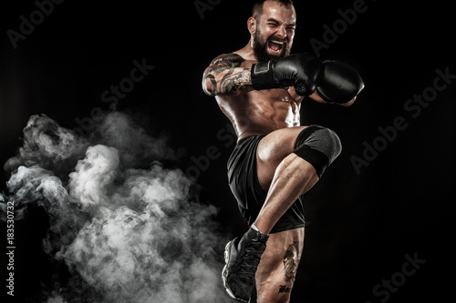 Obraz na płótnie Sportsman muay thai boxer fighting on black background with smoke