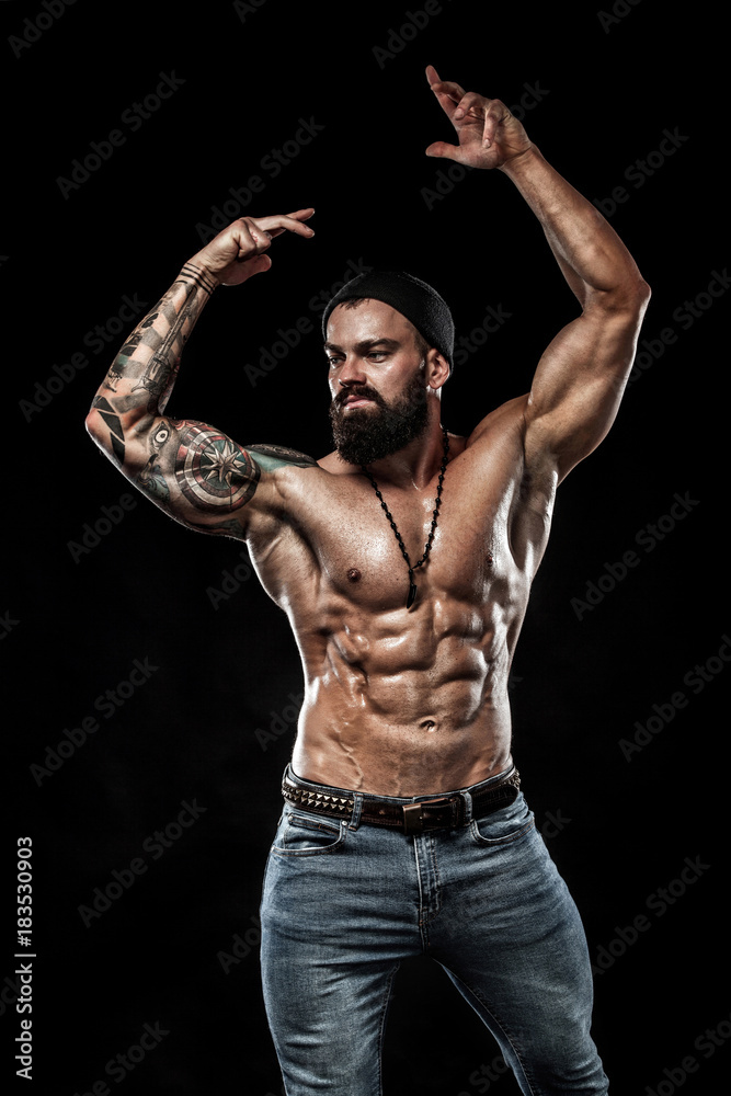 Handsome fit man posing wearing in jeans with tattoo. Sport and fashion concept isolated on black background. Handsome fit man posing wearing in jeans with tattoo. Sport and fashion concept isolated on black background.