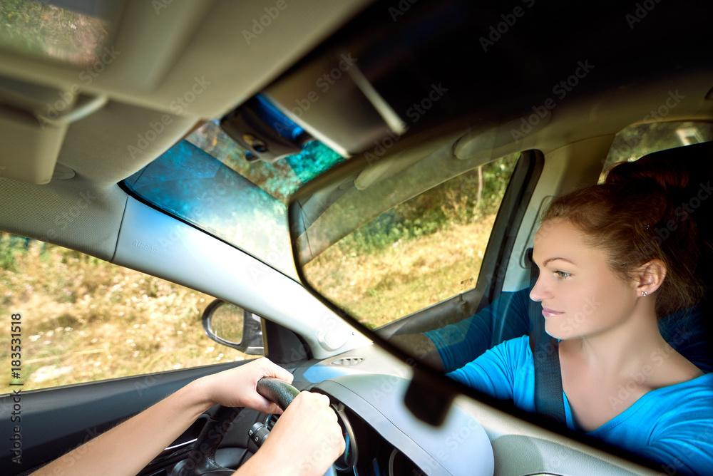 Naklejka premium Reflection in the mirror of beautiful young woman driving a car, free space. Business woman sitting in car and looking on road