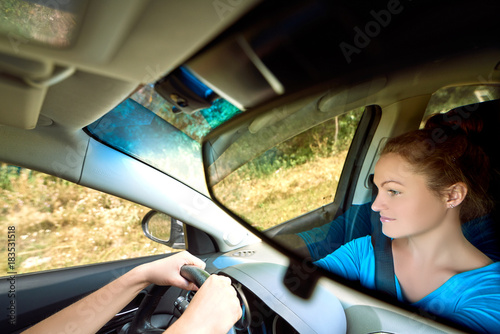 Reflection in the mirror of beautiful young woman driving a car, free space. Business woman sitting in car and looking on road