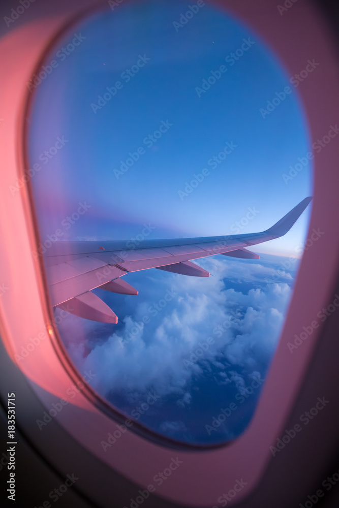 View from passenger's seat in airplane flying above clouds in dramatic sunset light. View from passenger's seat in airplane flying above clouds in dramatic sunset light.