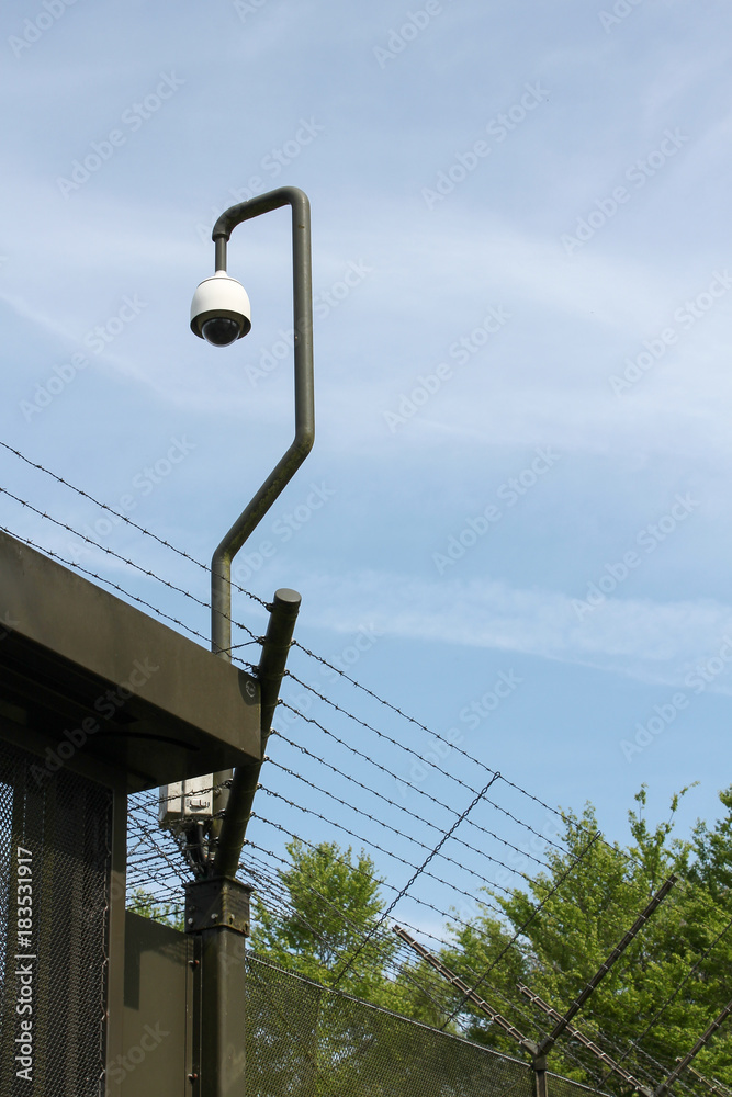 Obraz premium Camera and barbed wire fence surrounding a prison