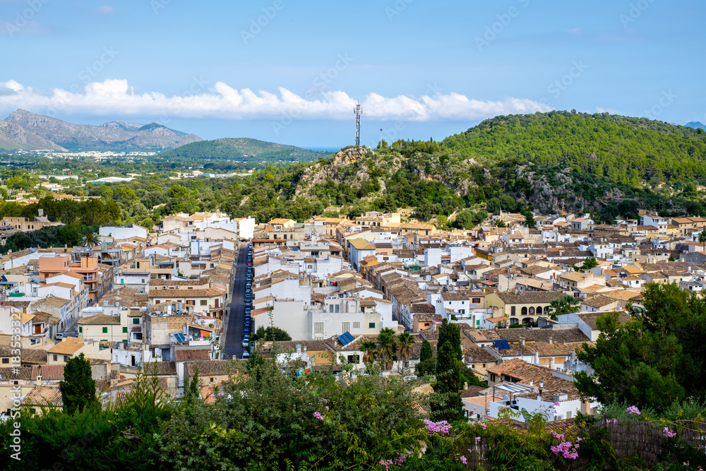 View of the city of Pollensa, Mallorca, downhill. Tops of roofs, straight streets, mountains.