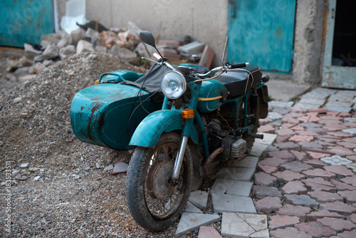 Old Soviet motorcycle with a stroller in a dump. photo