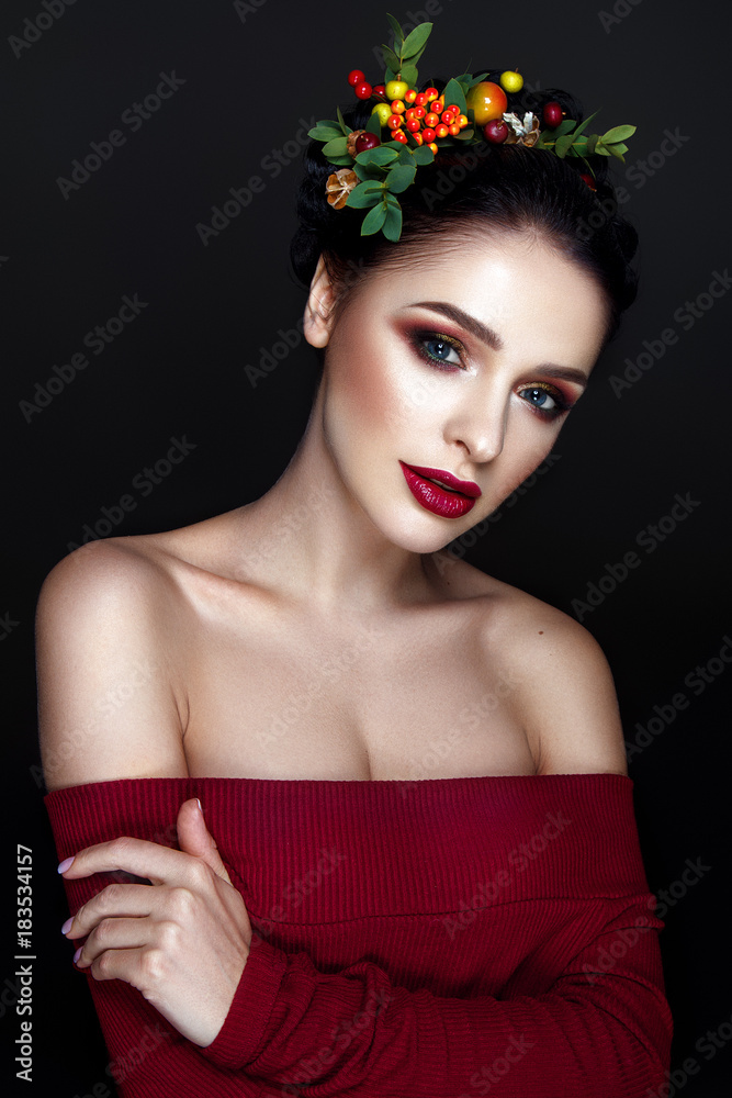 Naklejka premium Beautiful woman portrait with red and yellow berries on head and with black hair and red lips.