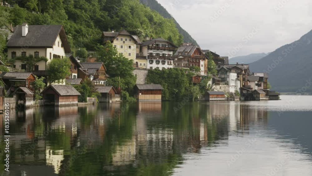Wide shot of reflection of mountain and houses in lake / Hallstatt, Austria Wide shot of reflection of mountain and houses in lake / Hallstatt, Austria