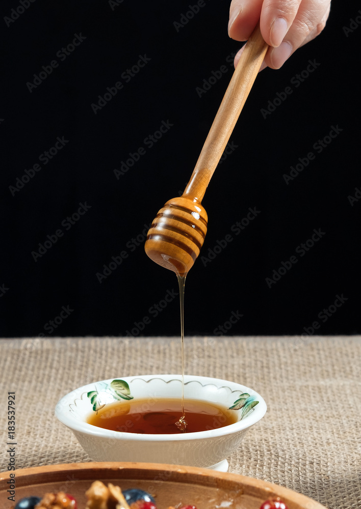 honey pouring from a spoon of honey in a bowl on a linen burlap honey pouring from a spoon of honey in a bowl on a linen burlap
