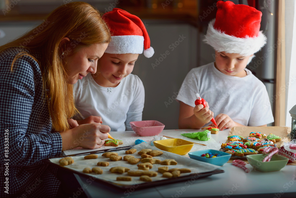 Mother with two happy children decorating cookies for holidays at home Mother with two happy children decorating cookies for holidays at home