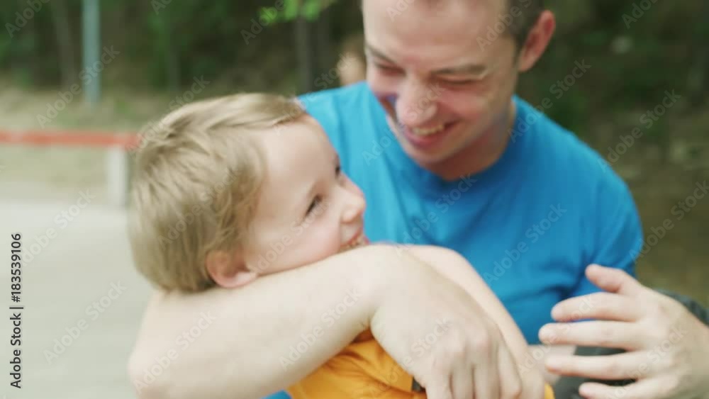 Close up slow motion shot of father cradling son in park / Plovdiv, Bulgaria Close up slow motion shot of father cradling son in park / Plovdiv, Bulgaria