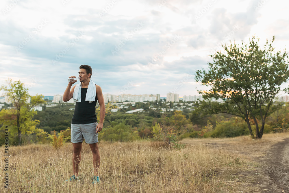 Healthy man drinking water on nature while resting 