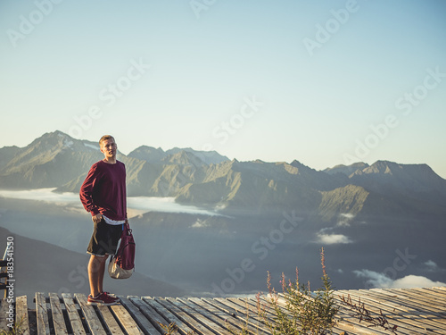 portrait of man with backpack standing on the top of the mountain above the clouds photo
