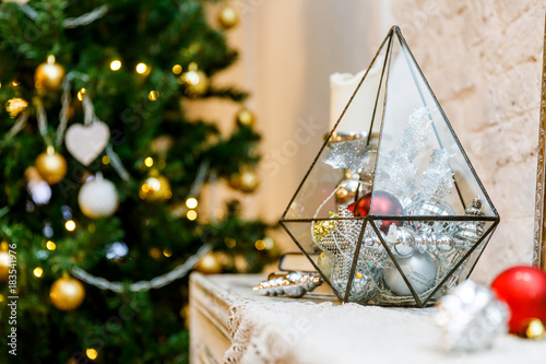 Terrarium glass with christmas decorations on the fireplace, lights bokeh